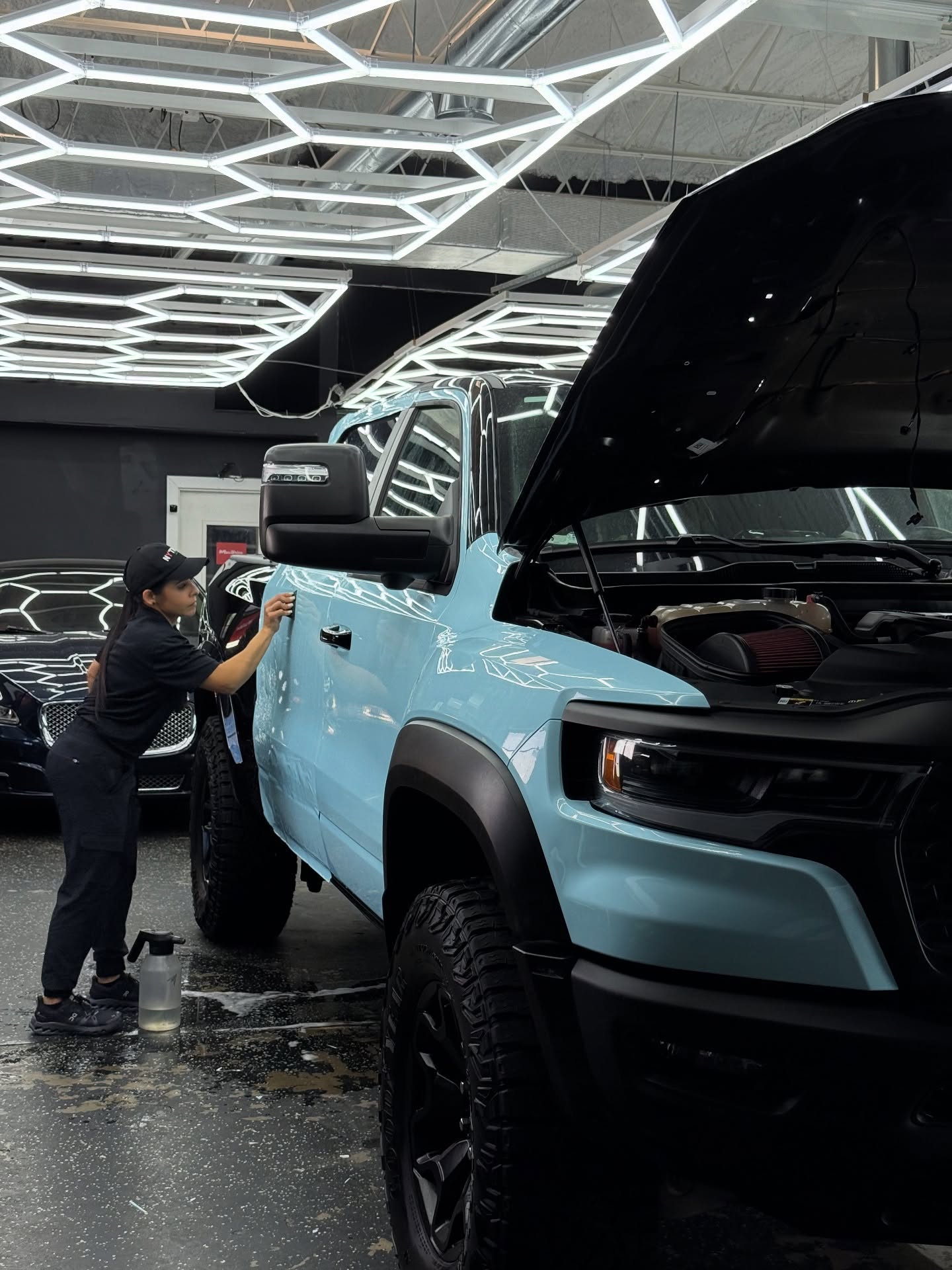 Auto Luxe installer smoothing paint protection film onto a light blue Ram TRX
